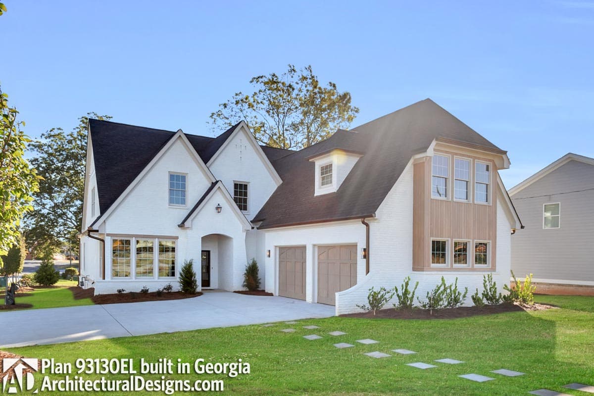 House plan exterior of two-story modern farmhouse with white brick, side-entry garage, gables, and wood accents.