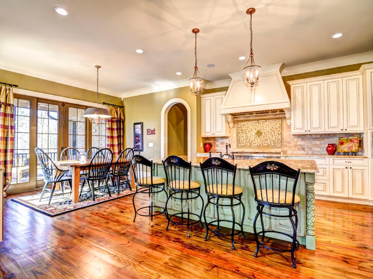 Kitchen and dining area with island seating, wood floors, french doors, and custom cabinetry.