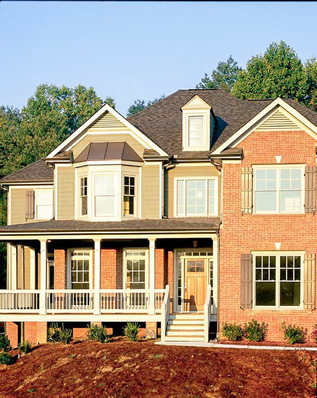 House plan exterior: Two-story home with wraparound porch, bay window, brick and siding facade, and gabled dormer.