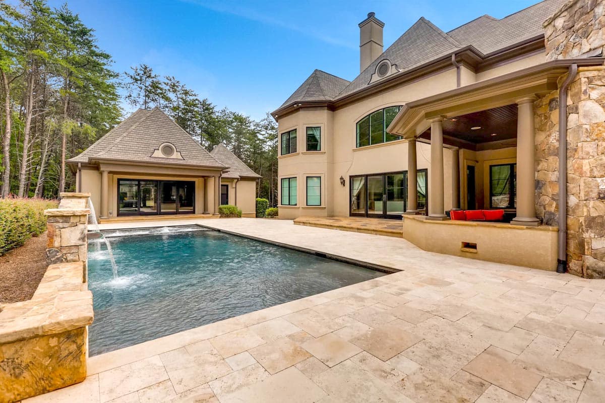 House plan exterior with swimming pool, stone accents, covered porch, and multiple gables.