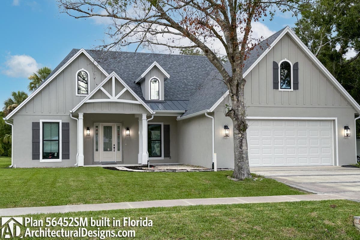 House plan exterior: Modern Farmhouse style, one story with a gabled front porch, arched dormer, and a three-car garage.