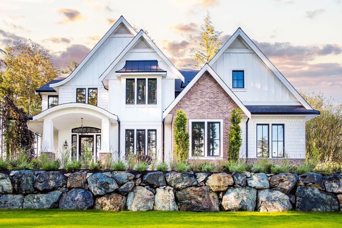 House plan exterior with two stories, board and batten siding, multiple gables, arched entry porch, and a brick accent gable.