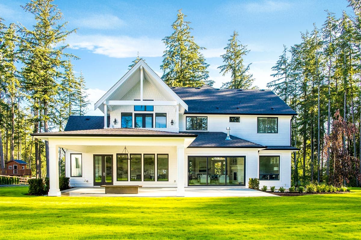 Two-story Modern Farmhouse with covered porch, large windows, gables, and steeply pitched rooflines.