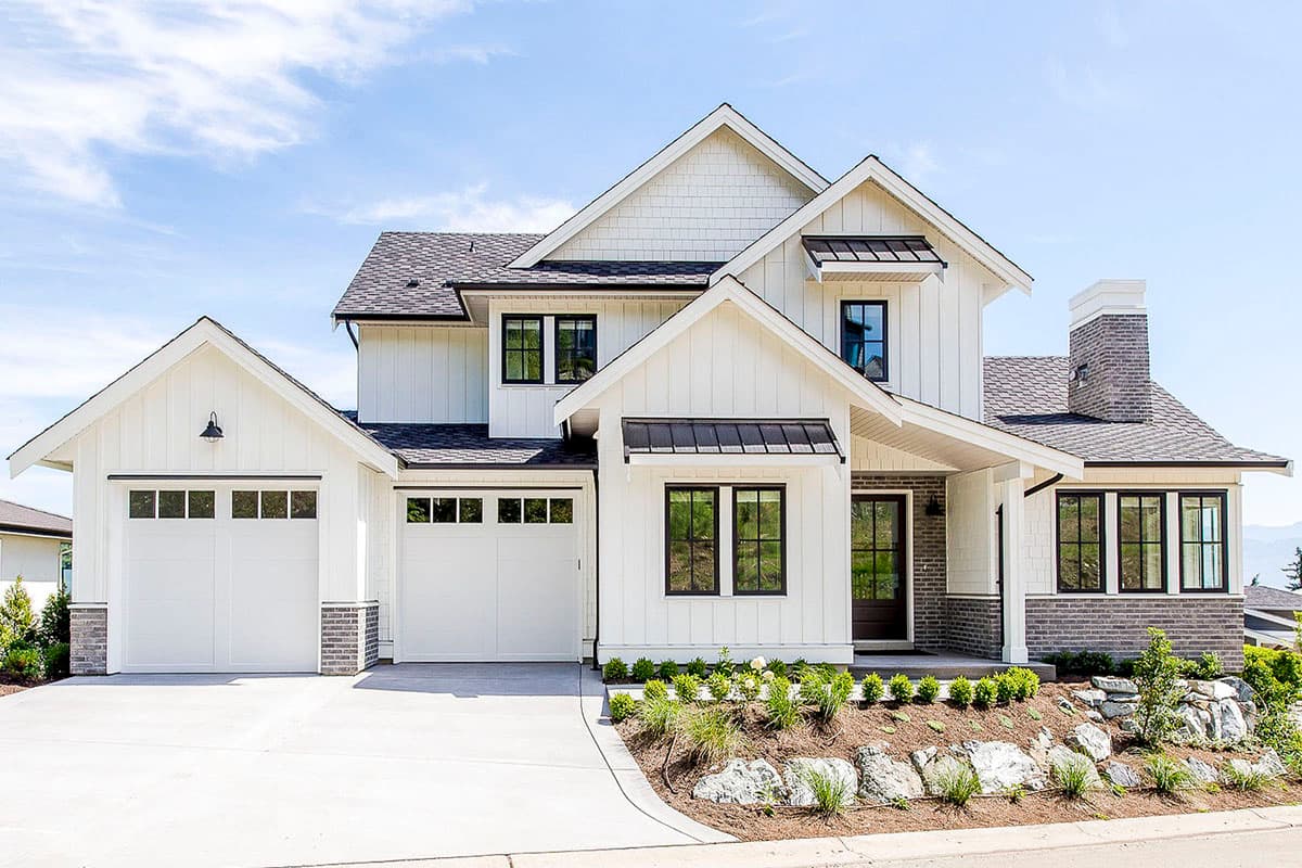 House plan exterior. Two-story Modern Farmhouse with gabled rooflines, dark-trimmed windows, and a detached garage with coach lighting.