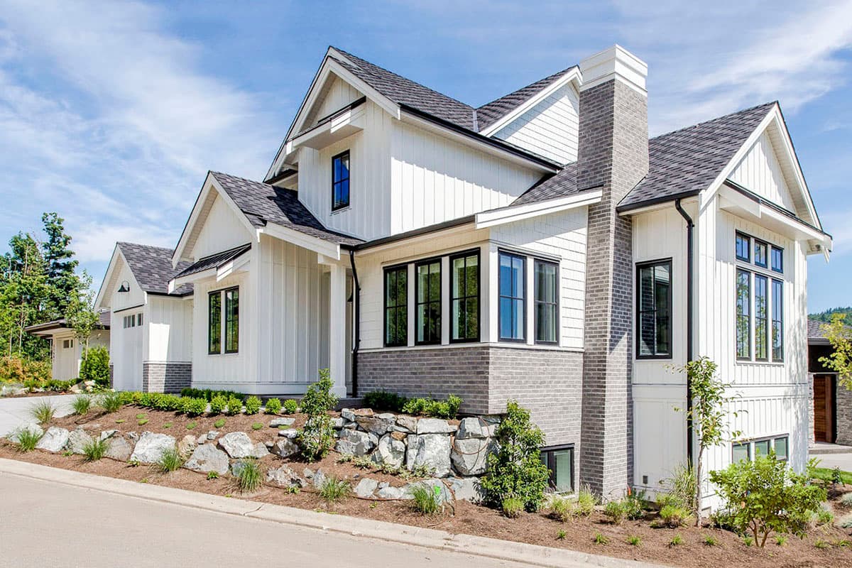Modern Farmhouse house plan exterior with vertical siding, gables, prominent chimney, and integrated garage.
