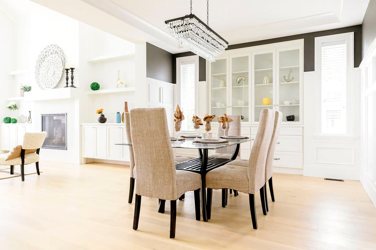 Dining area with glass table, upholstered chairs, built-in white cabinets, and fireplace.