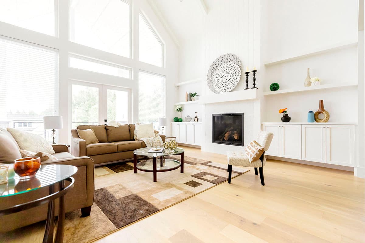 Living room with vaulted ceiling, fireplace, built-in cabinets, and large windows.