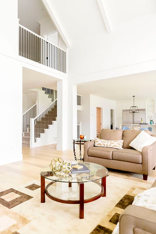 Interior view of an open-concept living area with a vaulted ceiling, staircase, and view into the kitchen.