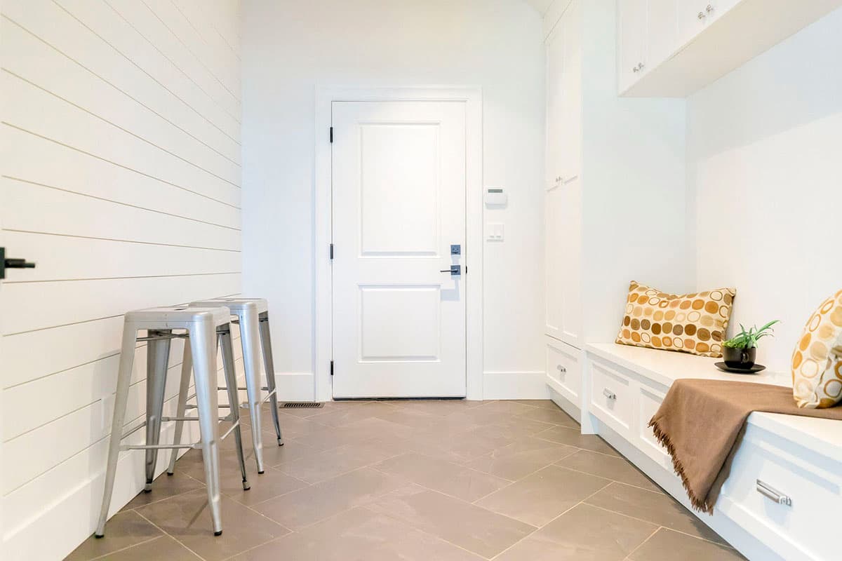 Mudroom with shiplap walls, bench seating, built-in cabinets, and a paneled door.