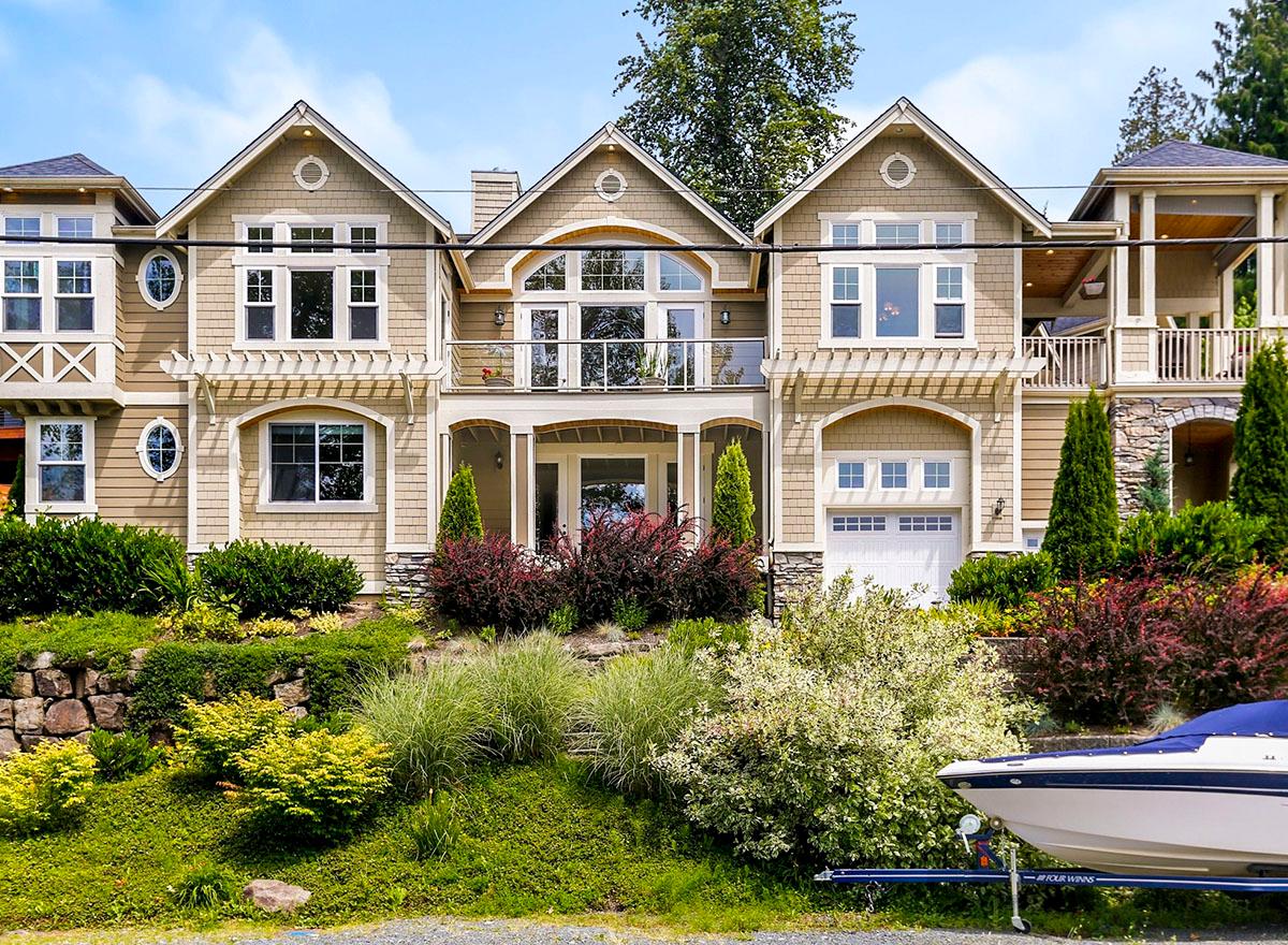 House plan exterior: Two-story home with gabled dormers, pergolas over arched garage and entrance, and a second-story balcony.