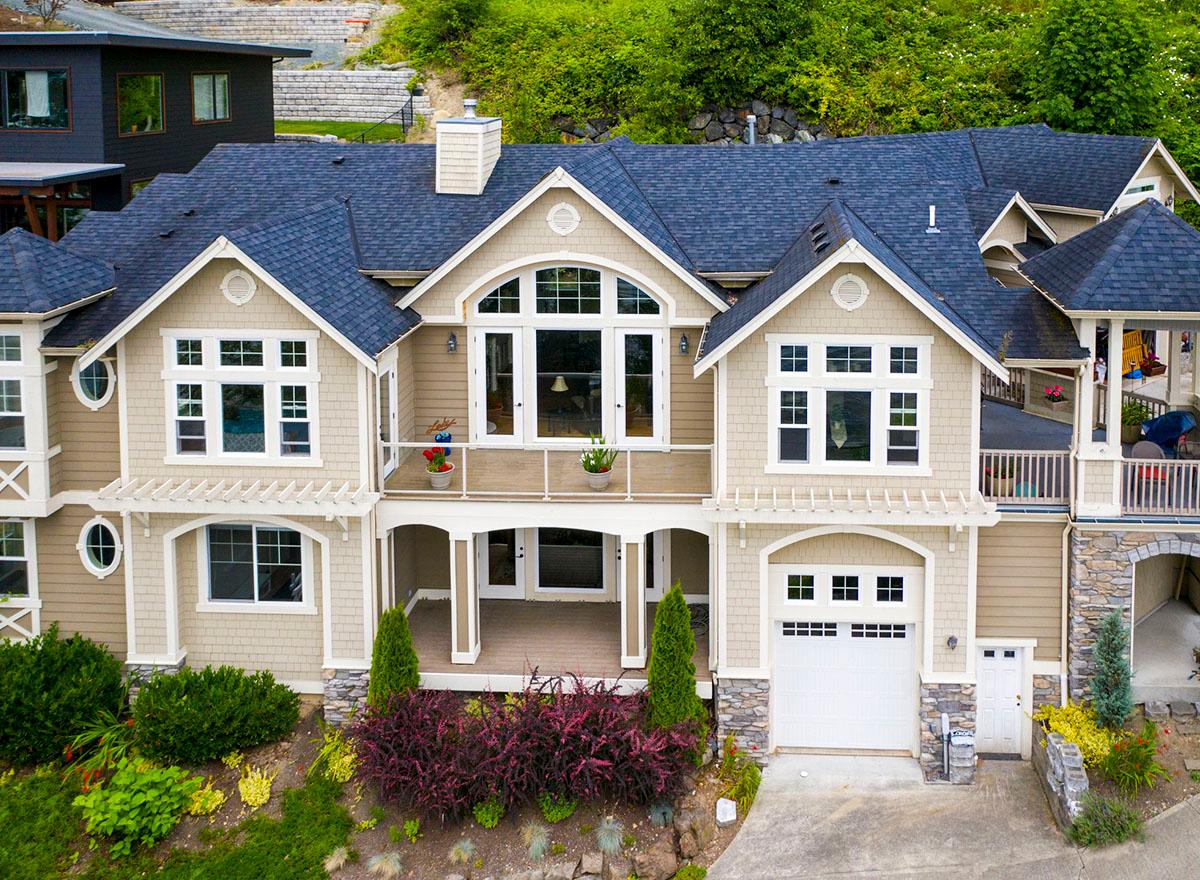 House plan exterior: Two-story home with a covered porch, arched windows, gables, dormers, and attached garage.