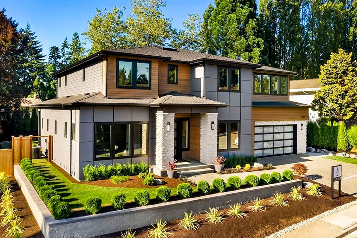 House plan exterior. Two-story modern house with a mix of wood and gray panel siding, a flat roof, and a glass-paneled garage door.