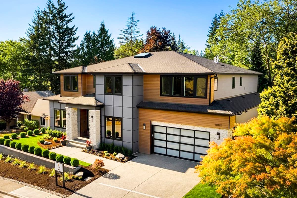 Modern two-story house plan exterior with wood and stone siding, a prominent entrance, and a glass garage door.