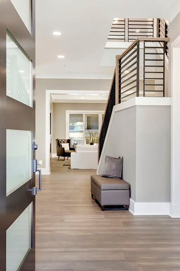 Entryway with open staircase featuring modern horizontal railings, a bench, and view into the living room with a fireplace.