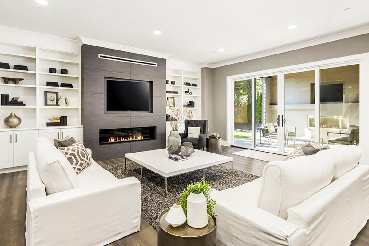 Living room with built-in bookshelves, a modern fireplace, and large sliding glass doors leading outside.
