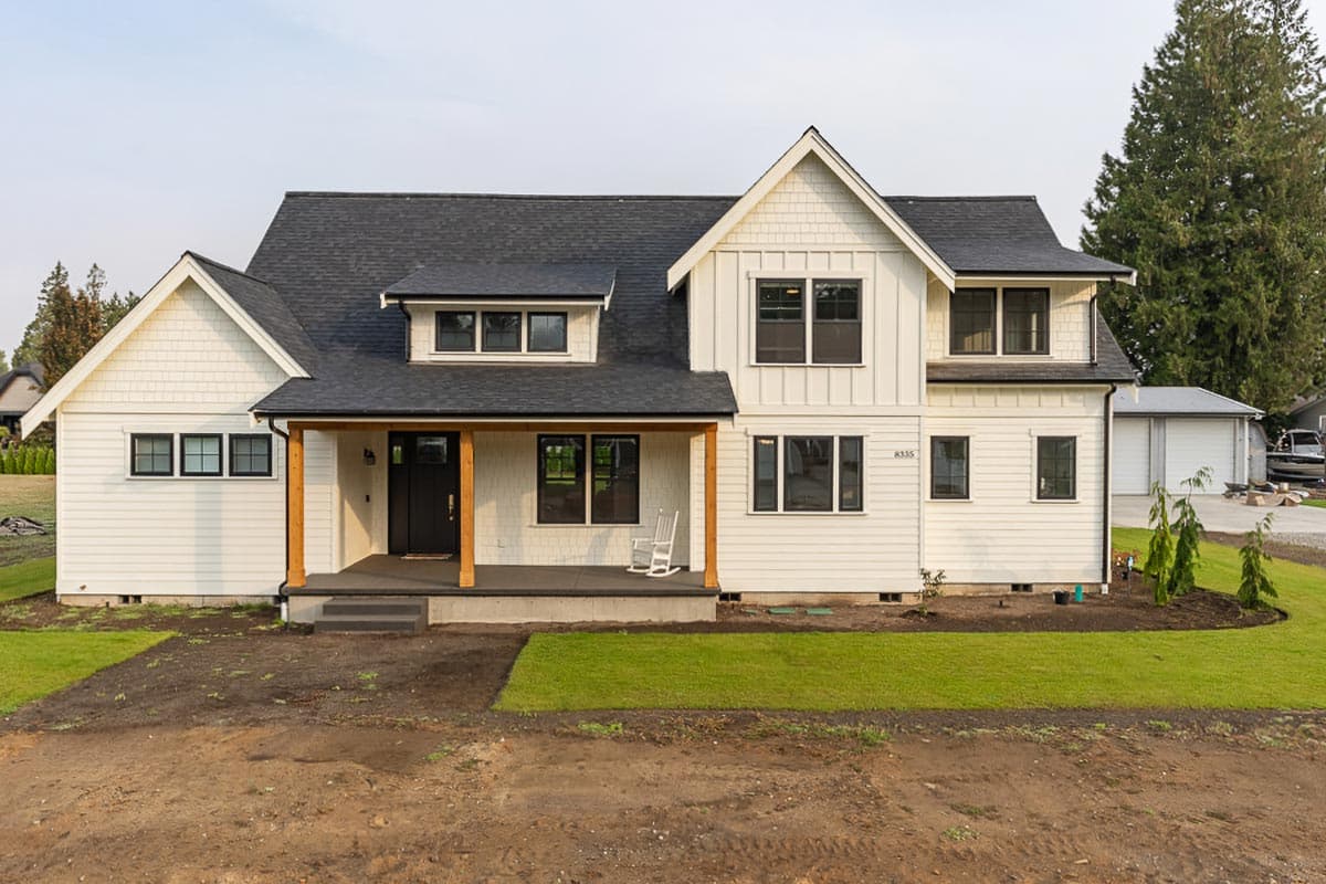 Modern Farmhouse exterior with a covered porch supported by wooden posts, dormers, and board and batten siding.