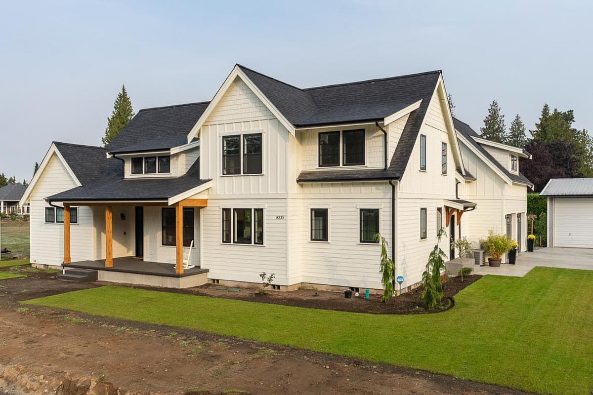 Modern Farmhouse style house plan exterior with prominent gables, a covered front porch with timber posts, and multiple dormers.