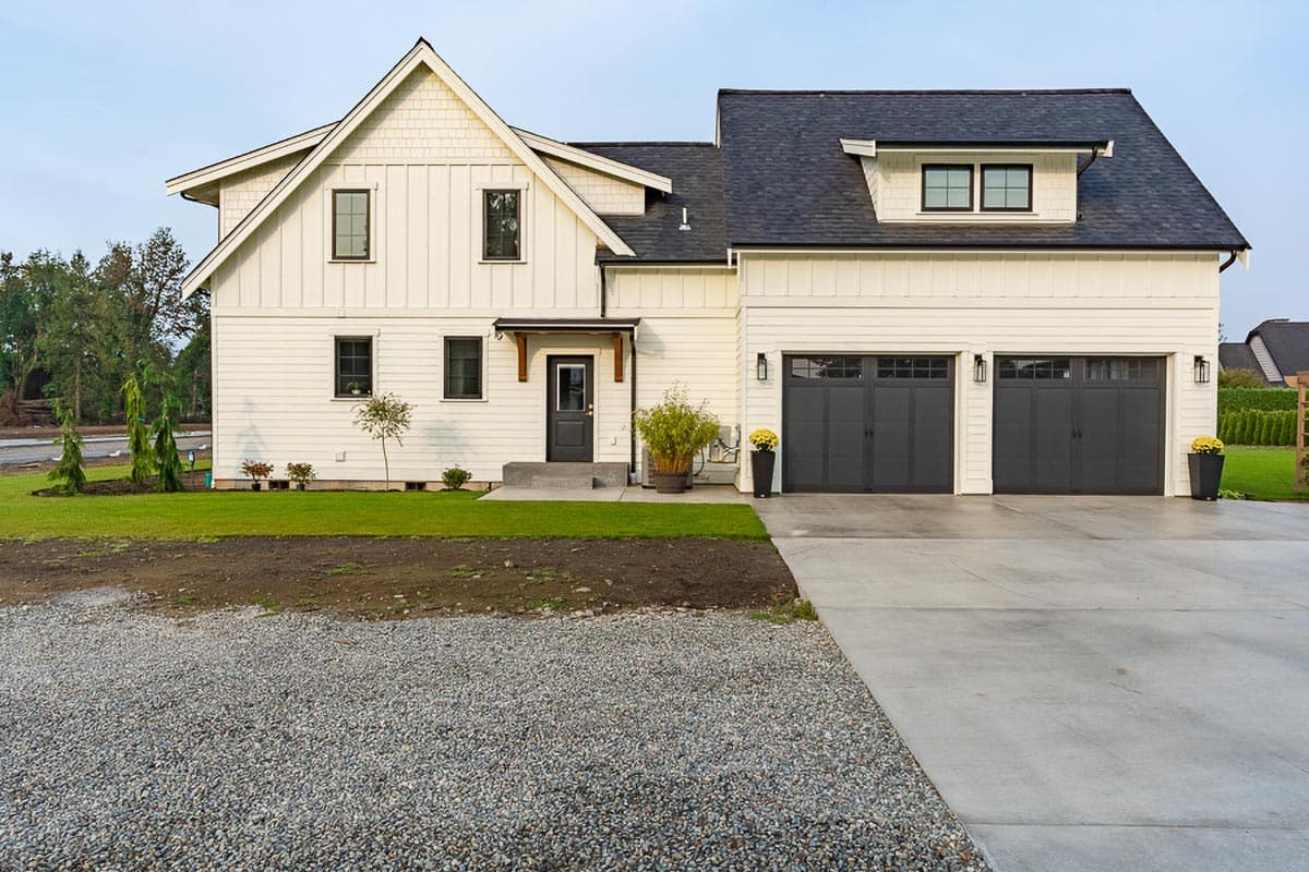 House plan exterior: Modern Farmhouse style, two stories, white board-and-batten siding, gable roof, dormer, and a three-car garage.