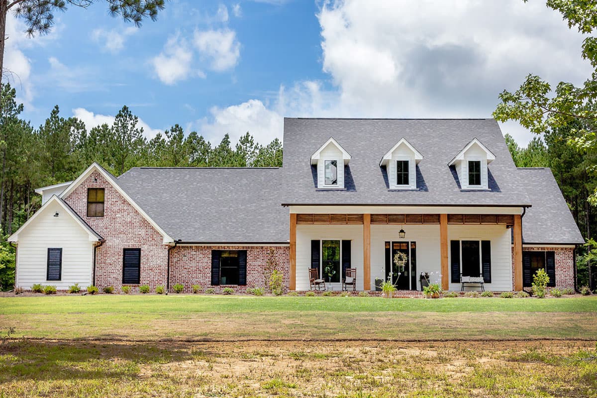 House plan exterior featuring a two-story Modern Farmhouse with a covered porch, gables, and dormers. Brick and white siding exterior.