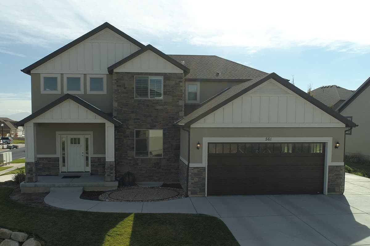 Two-story house plan exterior with gabled dormers, stone accents, and a covered front porch with a white door.
