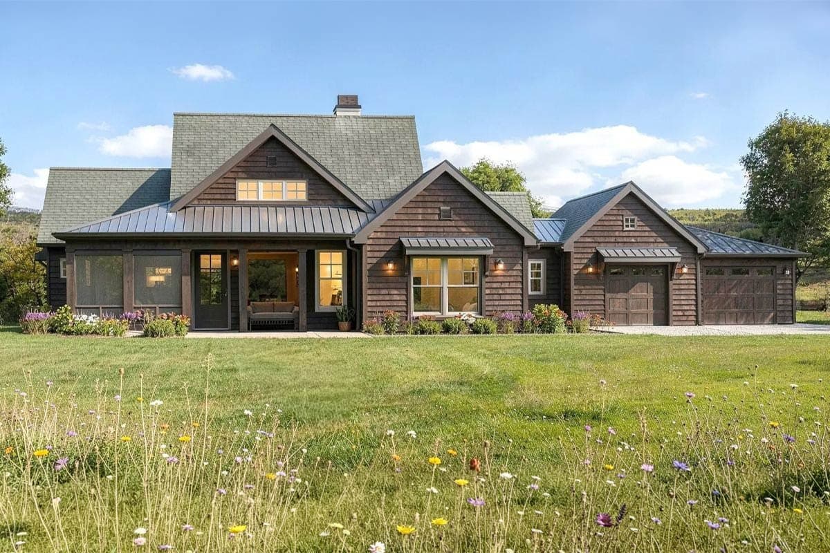 House plan exterior: Modern Farmhouse style with a covered porch, metal roof accents, and a three-car garage.
