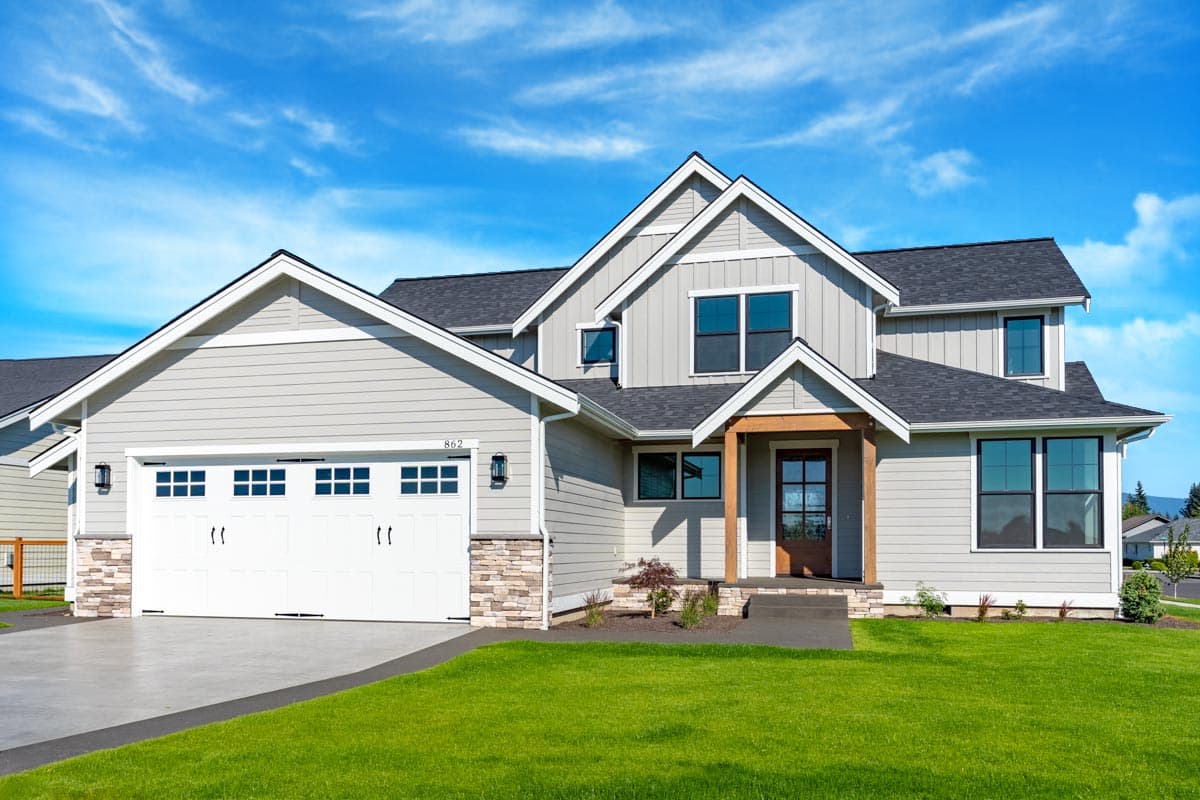 House plan exterior. Two-story Modern Farmhouse with gables, stone accents, and a covered porch with wooden supports.
