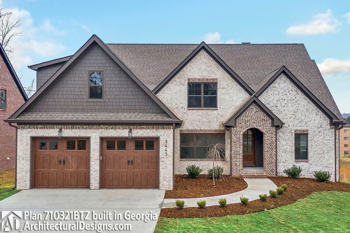 House plan exterior: Two-story Modern Farmhouse with white brick, arched entryway, and a triple-section garage.