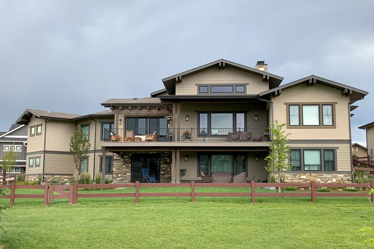 Craftsman-style house plan exterior with two stories, broad eaves, prominent gables, a main-level deck, and stone accents.