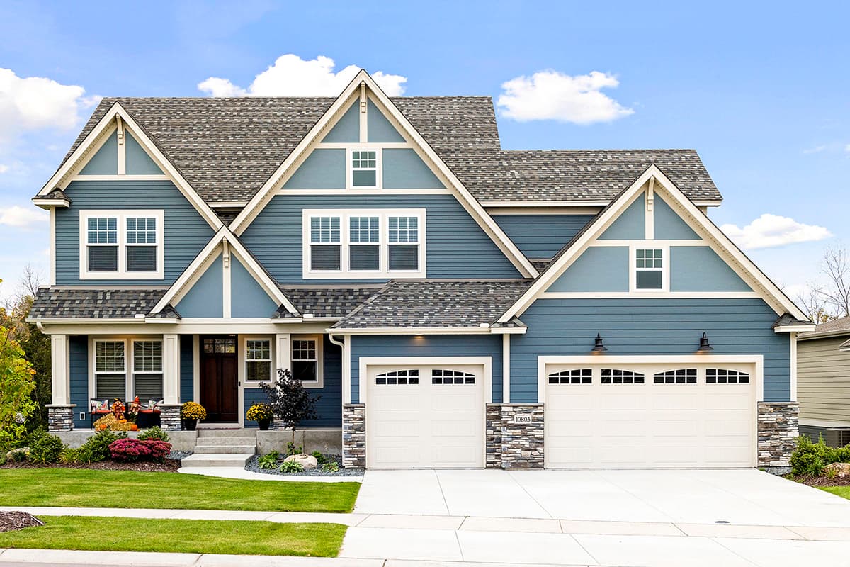 House plan exterior. Two-story home in Craftsman style. Features include multiple gables, a front porch, and a two-car garage.