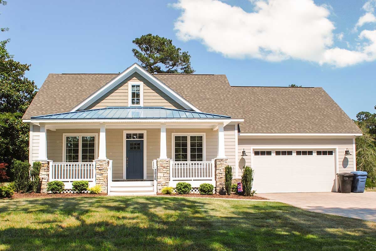 House plan exterior with Craftsman style. Features include a front porch with stone columns and a gabled roof. Attached garage is on the right.
