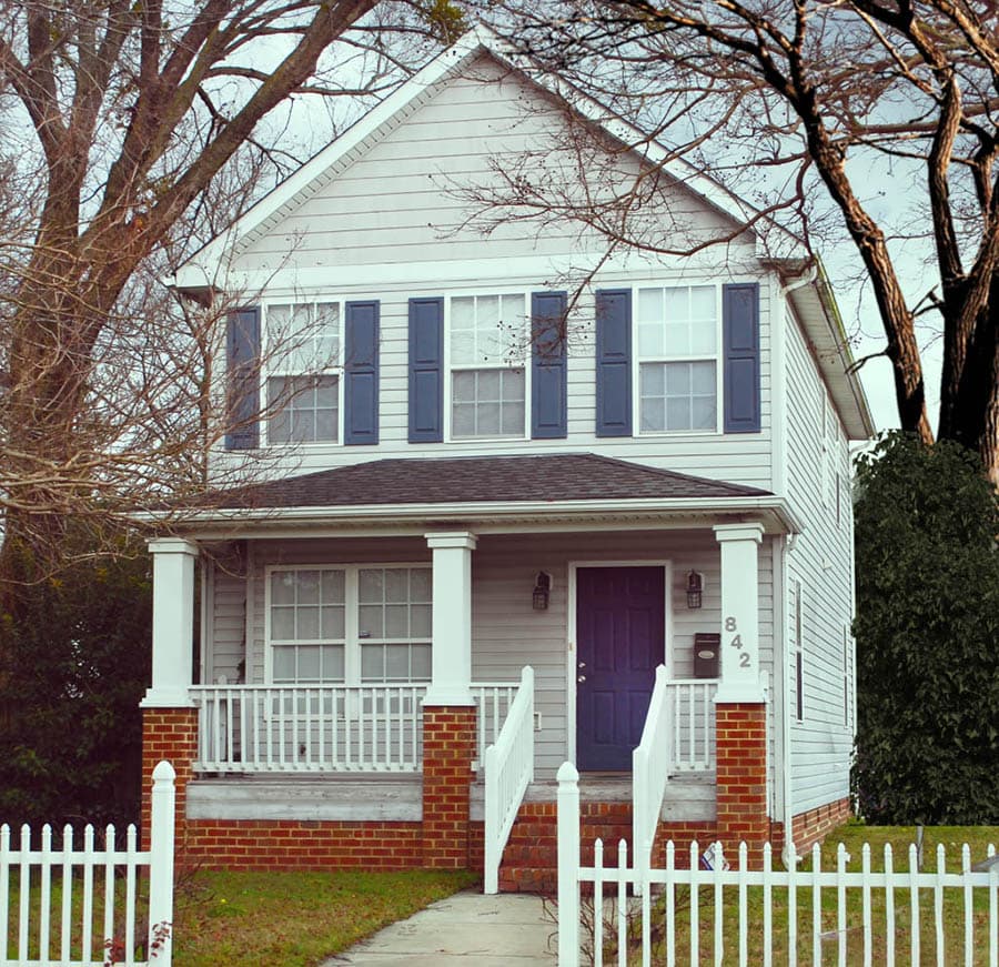 Two-story house plan exterior with gabled roof, front porch supported by columns, and blue shutters.