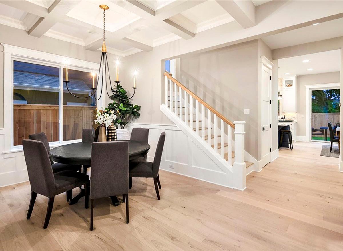 Dining area with coffered ceiling, chandelier, and view of staircase leading to upper level and kitchen.
