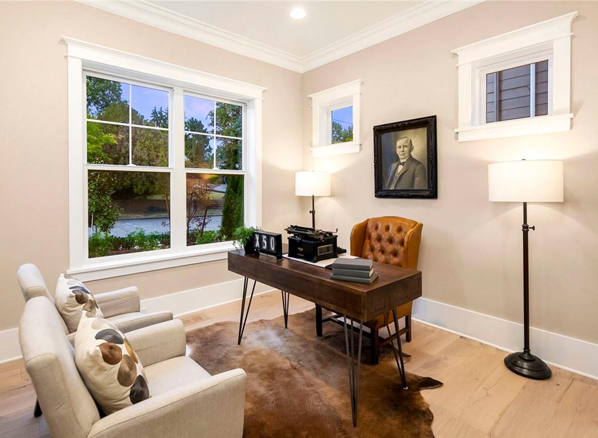 Office with large window, desk with vintage typewriter, leather chair, and two accent chairs.