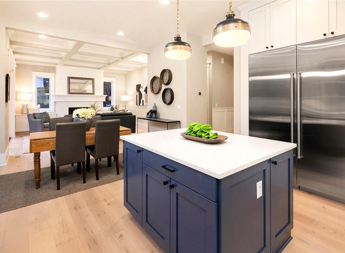 Kitchen island with blue cabinets and white countertop, adjacent dining area and living room with coffered ceiling.