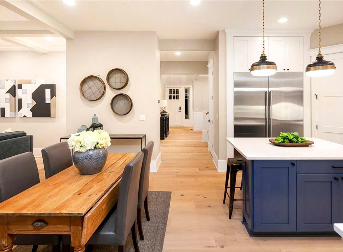 Open concept interior with dining table, kitchen island, stainless steel refrigerator, and entryway.