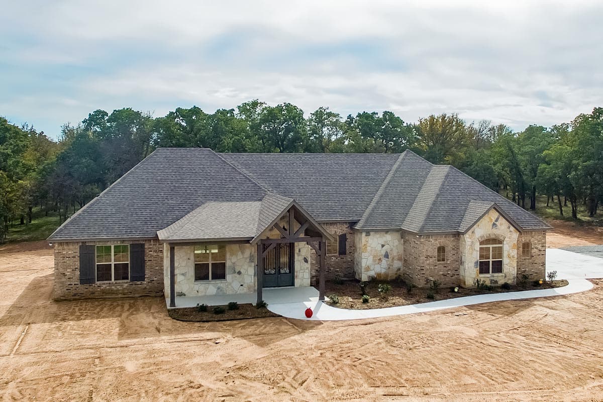 House plan exterior: Single-story home with stone and brick facade, gable roof, and timber-frame covered entryway.