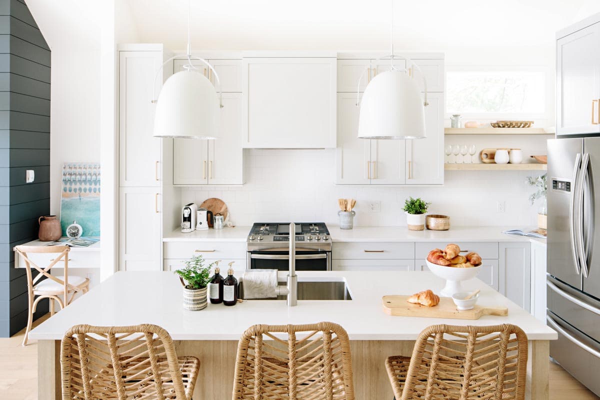 Modern kitchen with white cabinets, large island with seating, stainless steel appliances, and pendant lighting.