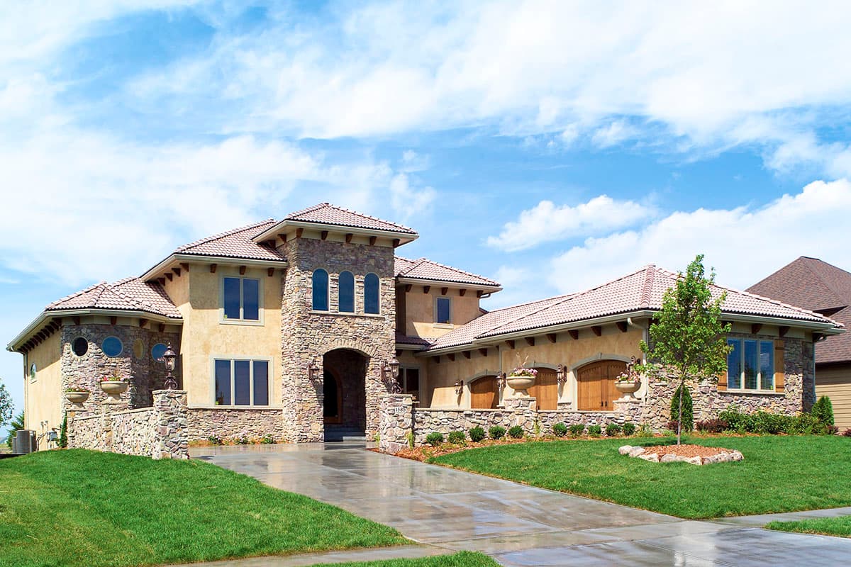 House plan exterior. Two-story Mediterranean-style home with stone facade, arched entry, multiple gables, and tile roof.