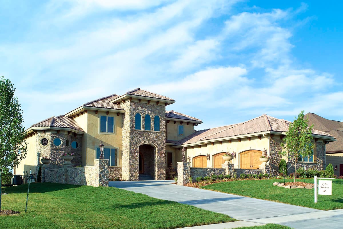 House plan exterior: Mediterranean style, two stories, arched entryway, stone accents, and tile roof.