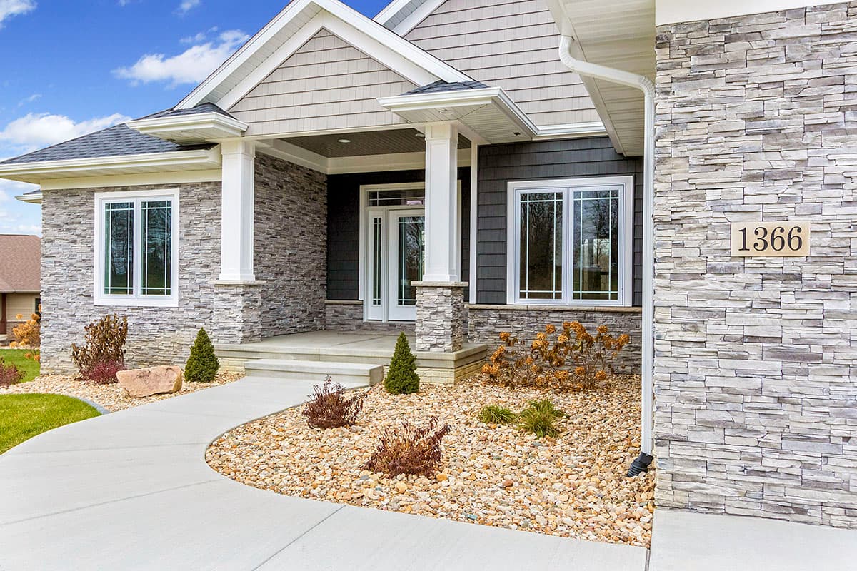 House plan exterior with stone and shingle siding, covered entry with columns, and multiple windows.
