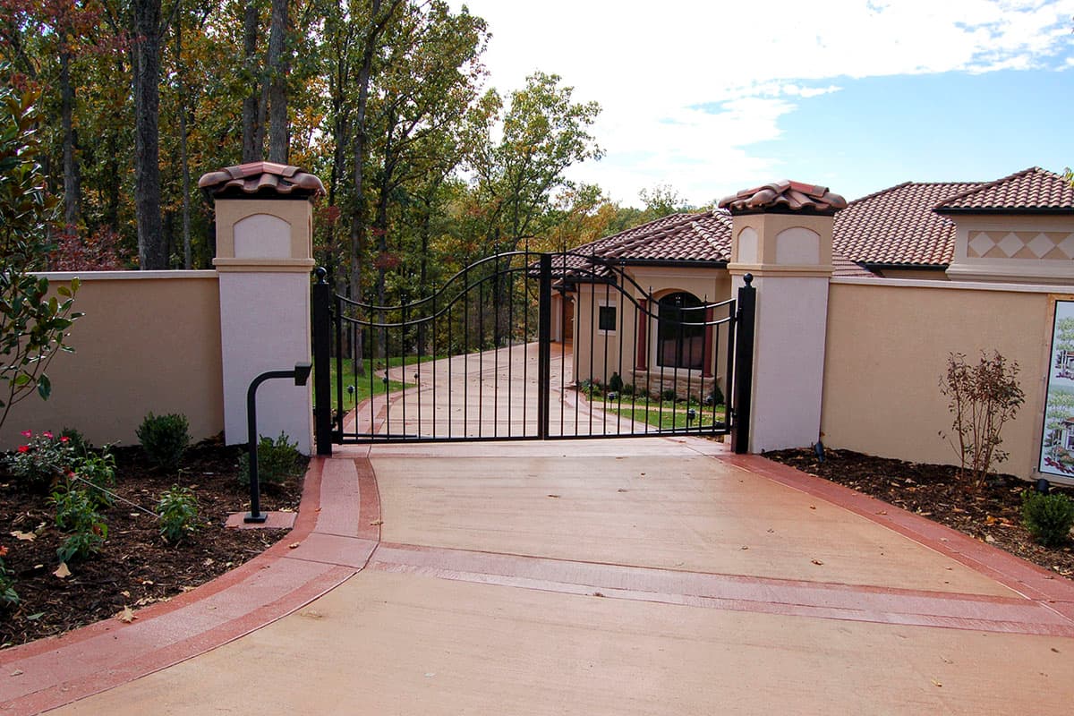 House plan exterior with decorative wrought iron gates, stucco walls, tile roof, and arched entryway.