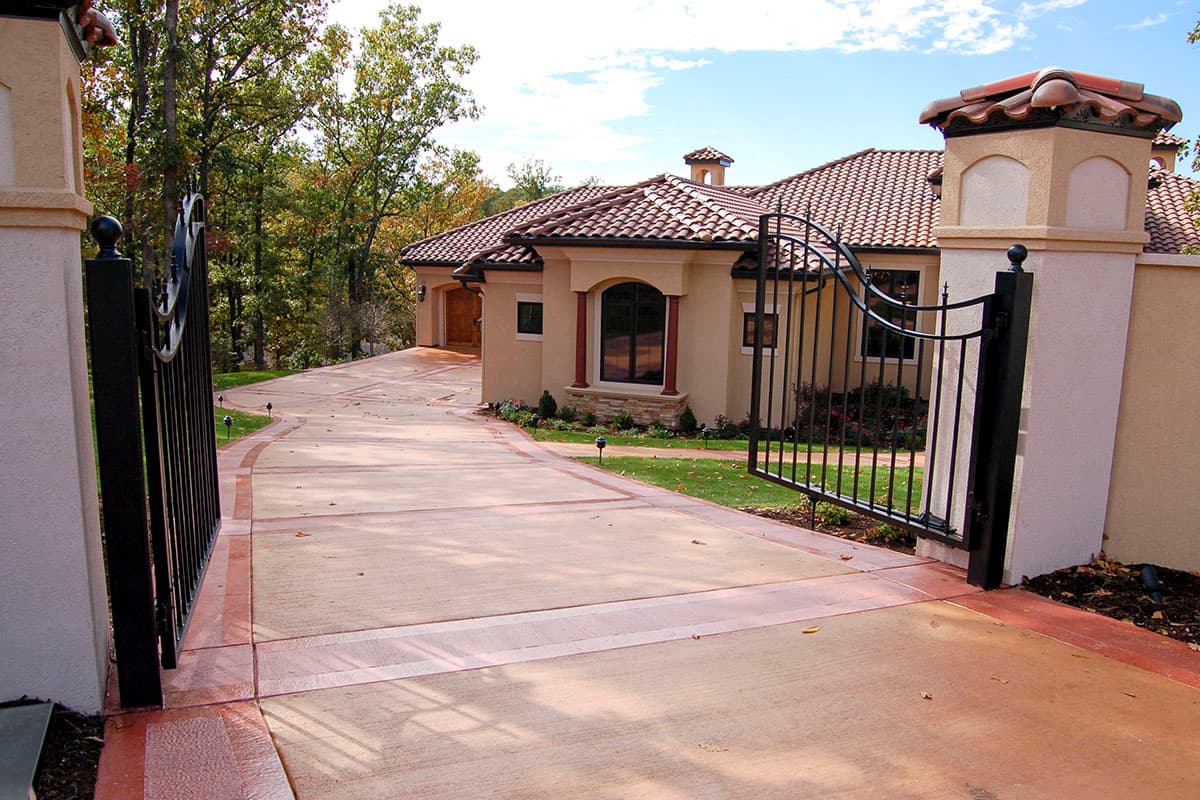 House plan exterior: one-story Mediterranean style with a tiled roof, stucco facade, arched window, and wrought iron gate.