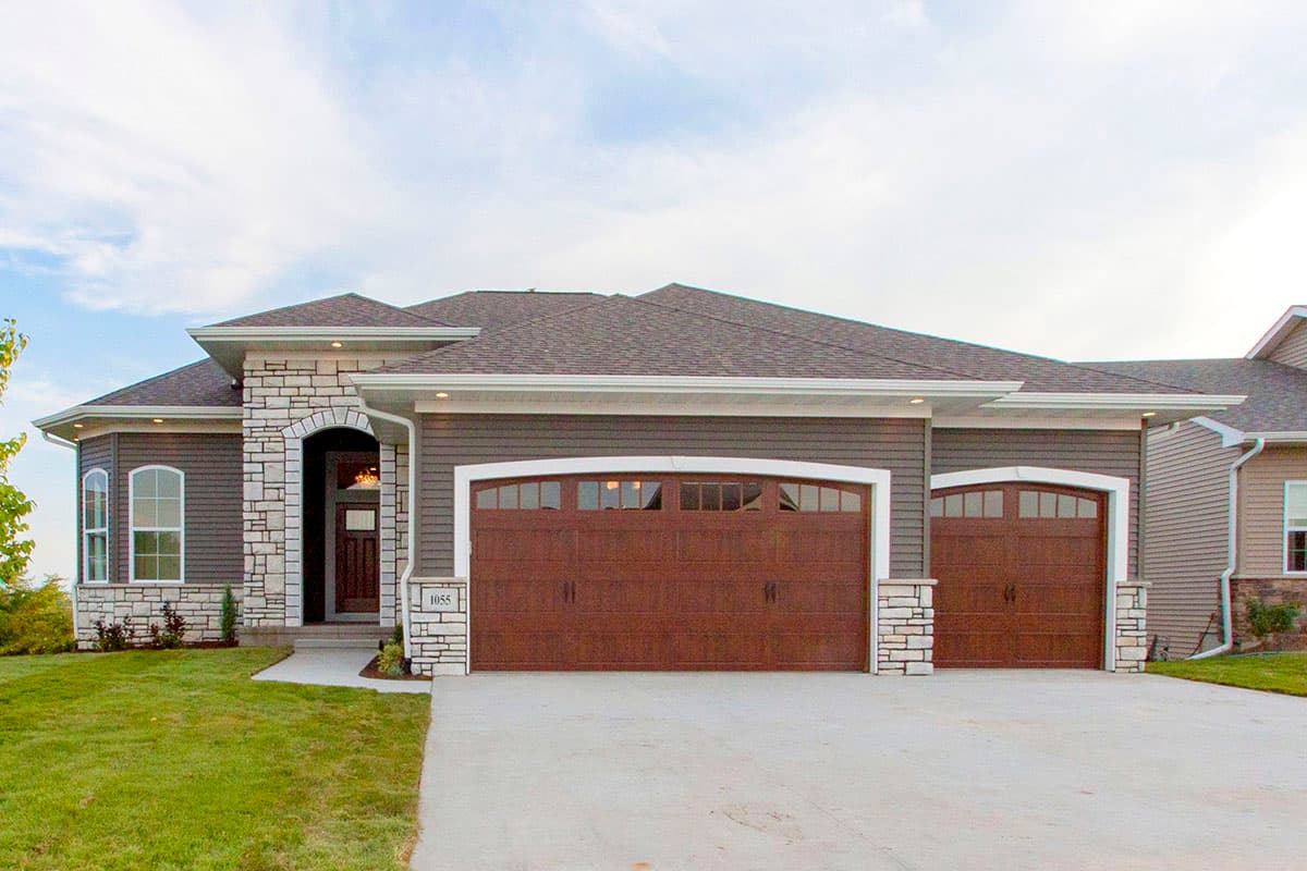 House plan exterior: Ranch style with a covered entry featuring stone archway, two-car garage, and stone accents.