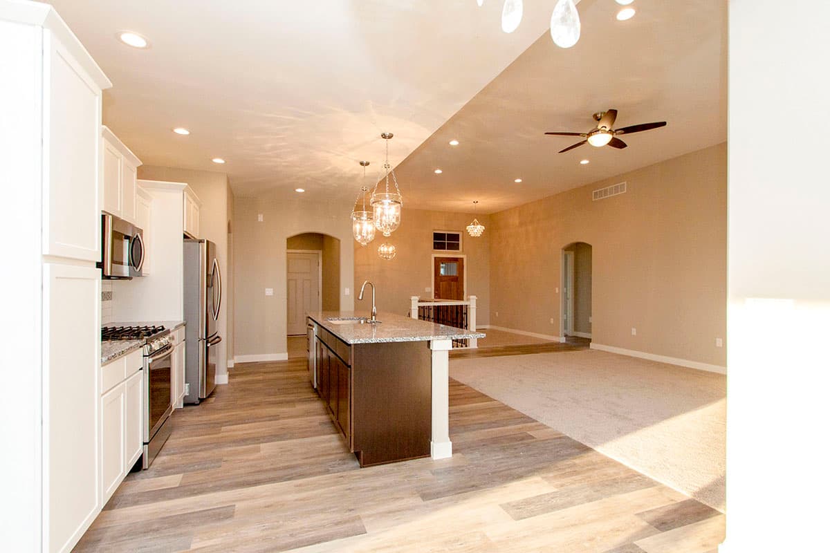 Open concept interior with kitchen island, stainless steel appliances, and vaulted ceiling.