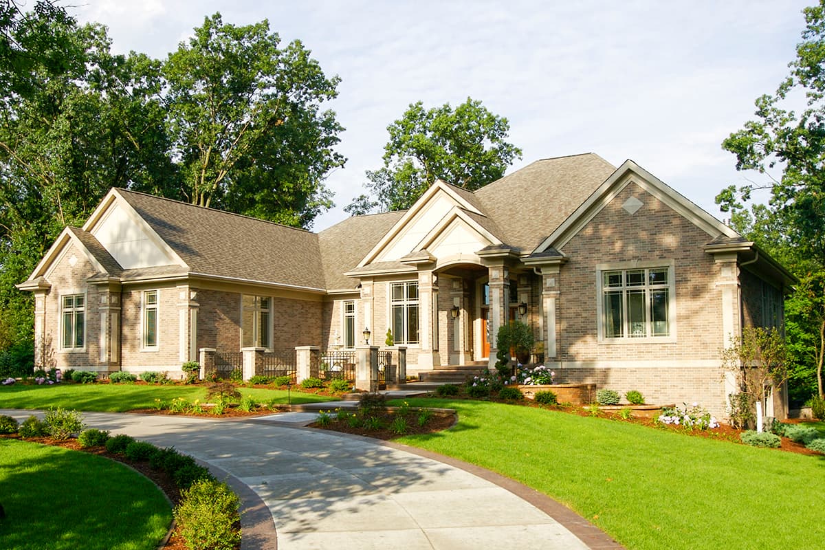 House plan exterior: Contemporary style, one-story, brick facade, gabled roof, arched entryway with columns, and large windows.