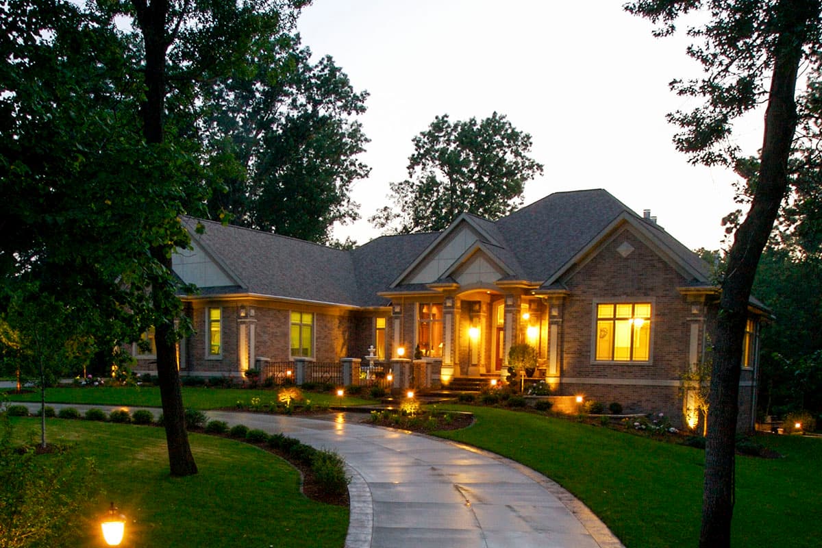 House plan exterior: Brick ranch with covered entry, gabled dormers, and a winding driveway.