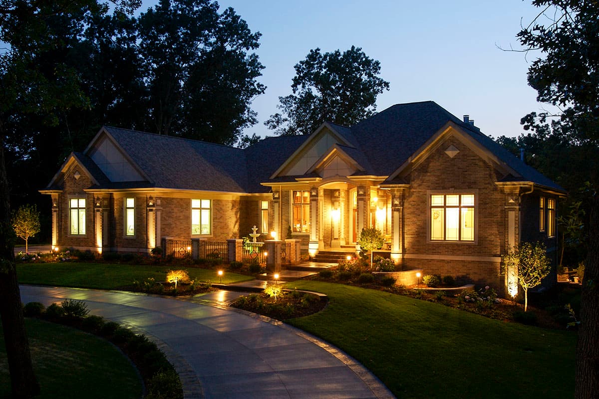 House plan exterior: single-story brick home with gabled roof, covered entry with columns, and prominent windows.