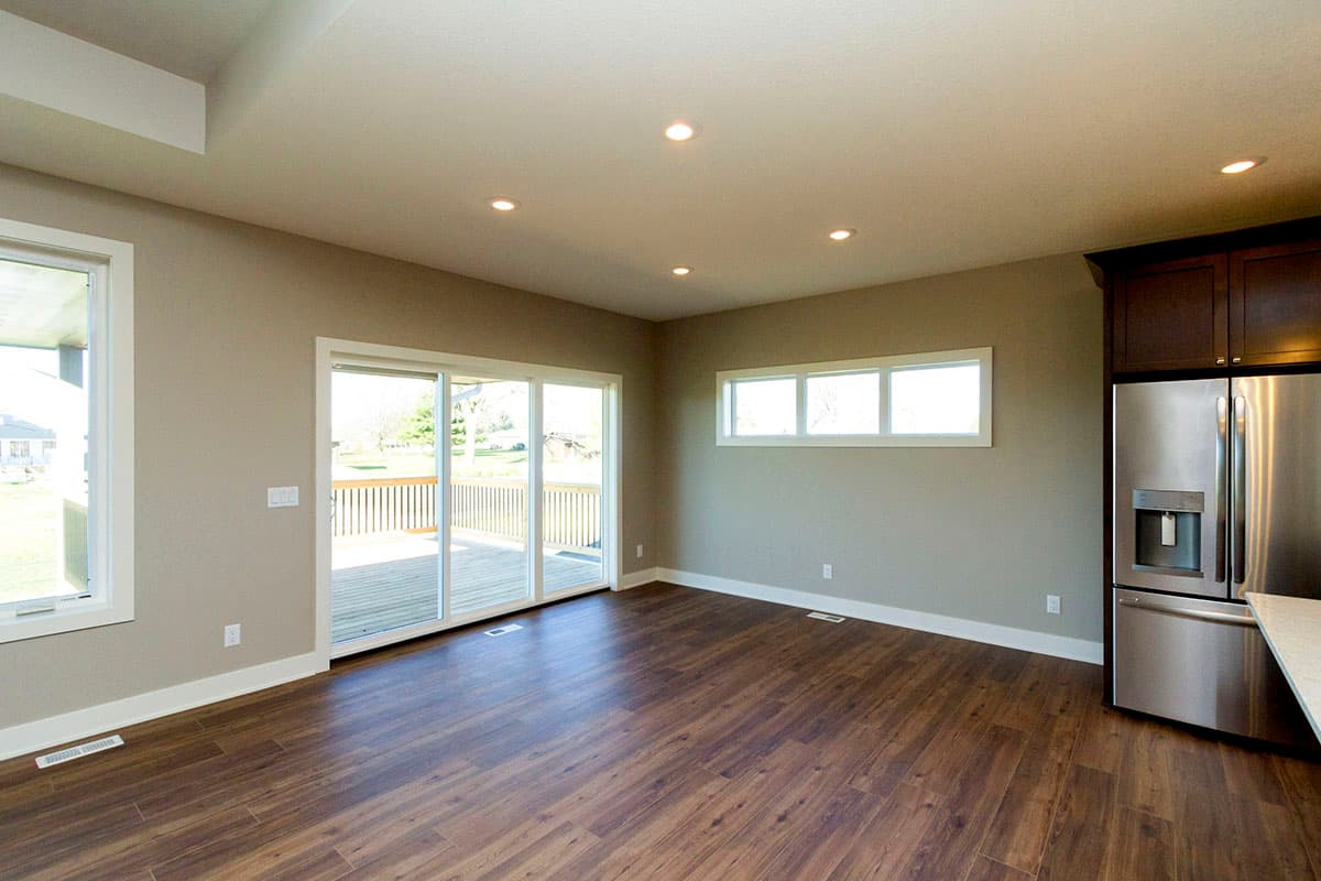 Open concept living area with sliding glass doors to deck, wood flooring, and stainless steel refrigerator.