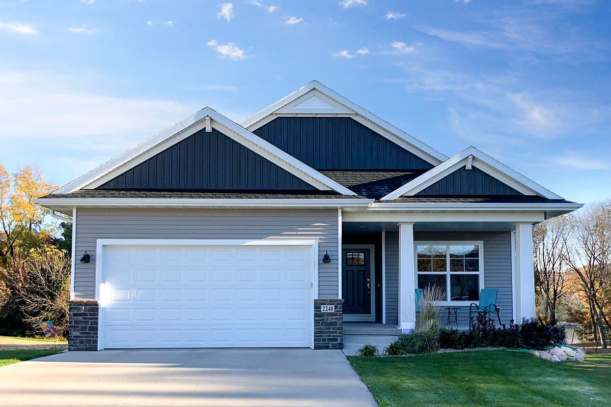 House plan exterior featuring a one-story design with a gable roof, covered porch, and attached garage. Exterior includes decorative gables.