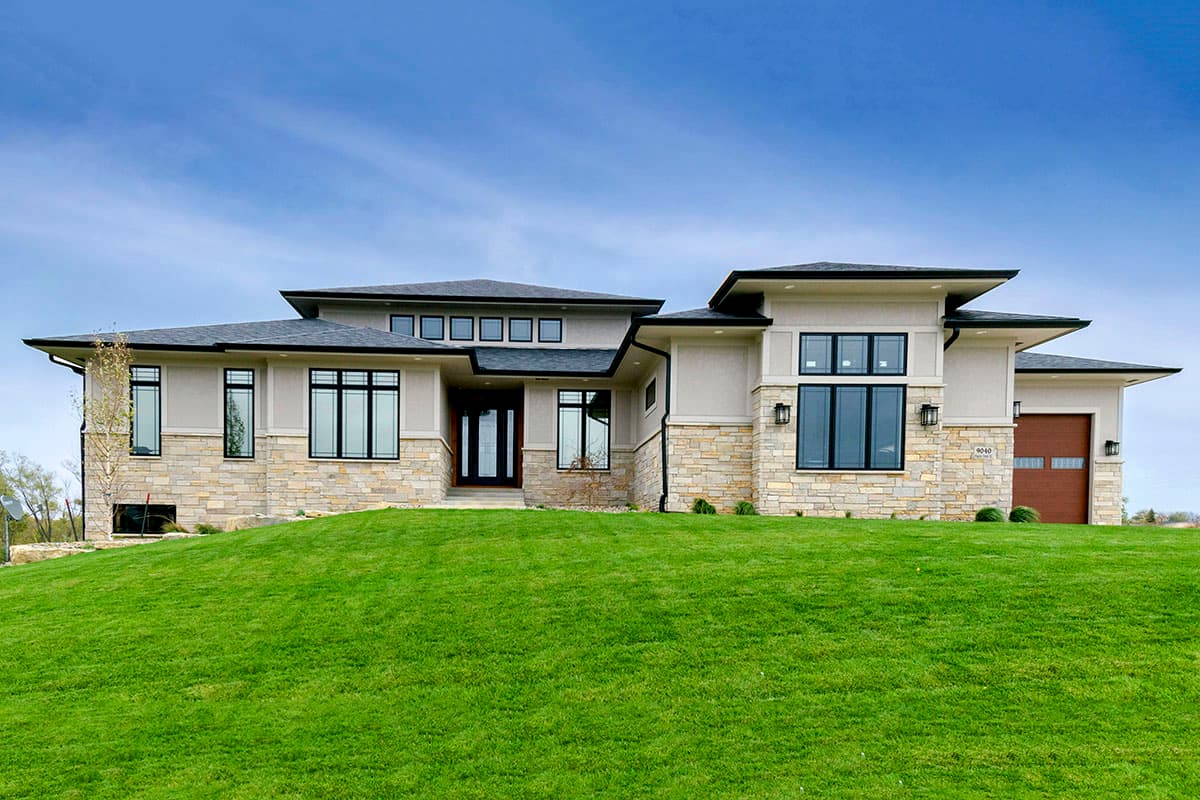 House plan exterior. Modern style, single story, with flat rooflines, stone veneer accents, and a front-facing garage.